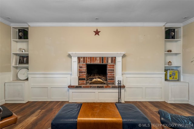 living room featuring built in shelves, ornamental molding, dark wood-type flooring, and a brick fireplace