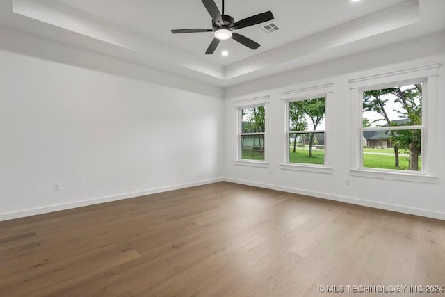 empty room featuring wood-type flooring, a tray ceiling, and ceiling fan