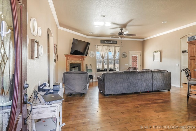 living room featuring ceiling fan, dark wood-type flooring, a textured ceiling, and ornamental molding