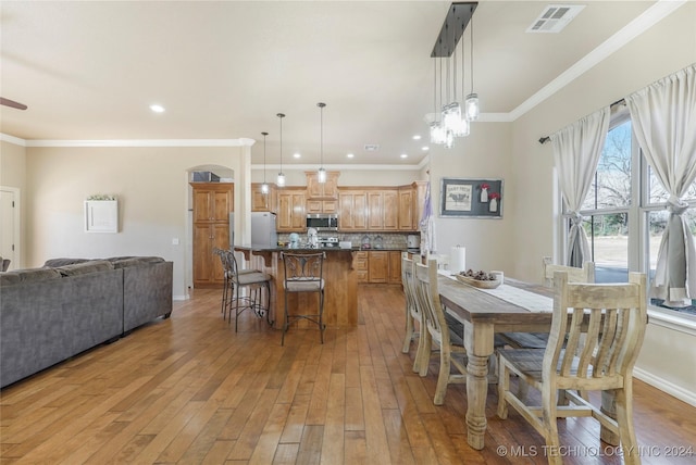 dining space with light hardwood / wood-style floors and crown molding