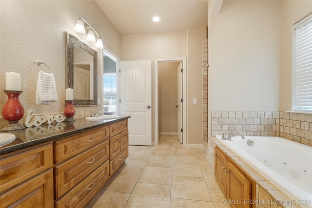 bathroom with tile patterned flooring, plenty of natural light, vanity, and tiled bath