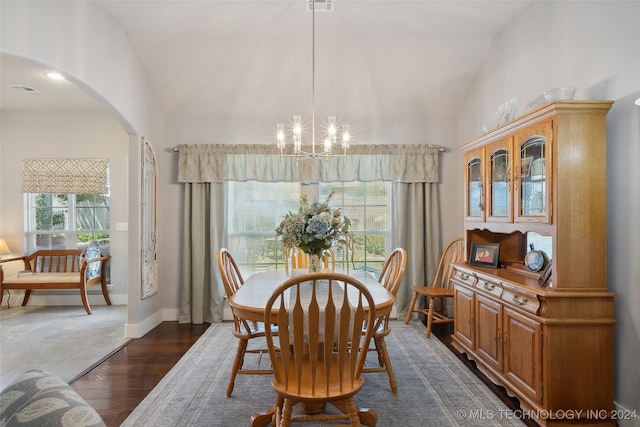 dining space with high vaulted ceiling, dark hardwood / wood-style floors, and an inviting chandelier