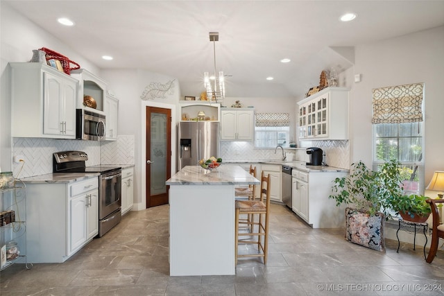 kitchen featuring pendant lighting, a center island, white cabinets, sink, and stainless steel appliances