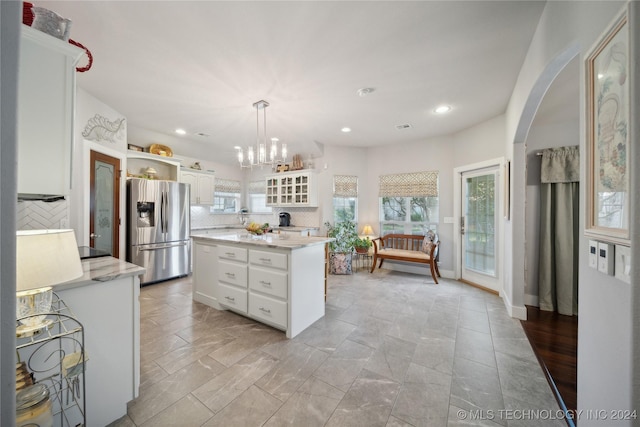 kitchen with backsplash, stainless steel fridge with ice dispenser, white cabinets, and a healthy amount of sunlight