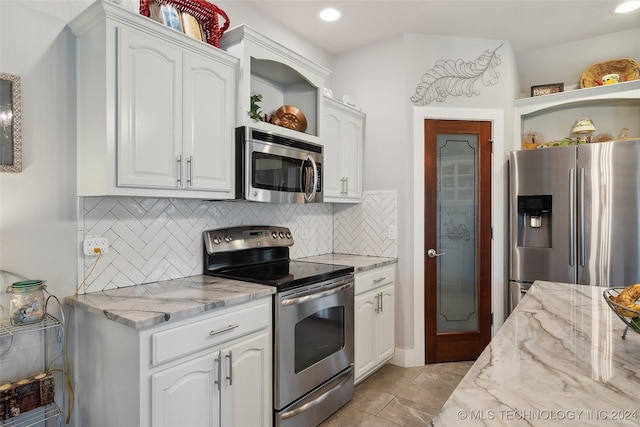 kitchen featuring light stone countertops, backsplash, white cabinetry, and stainless steel appliances