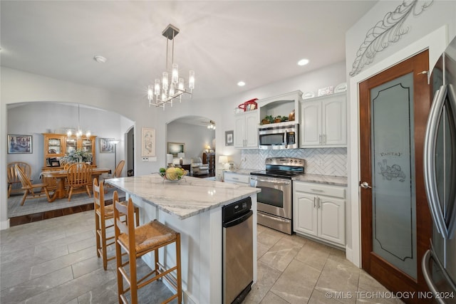 kitchen with decorative light fixtures, a kitchen breakfast bar, white cabinetry, and appliances with stainless steel finishes