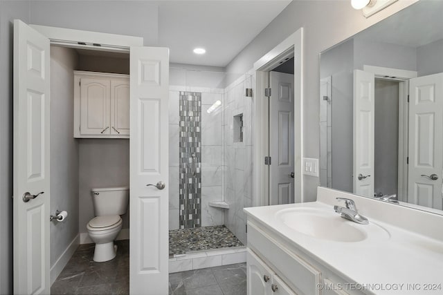 bathroom featuring tiled shower, vanity, and toilet