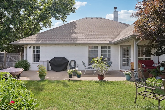 back of property featuring a lawn and a patio