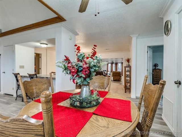 dining space featuring a textured ceiling, ceiling fan, and crown molding