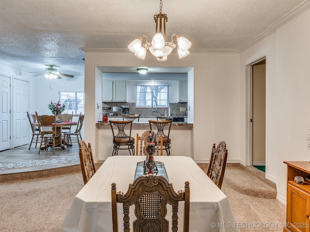 dining space featuring ceiling fan with notable chandelier, sink, a textured ceiling, and crown molding