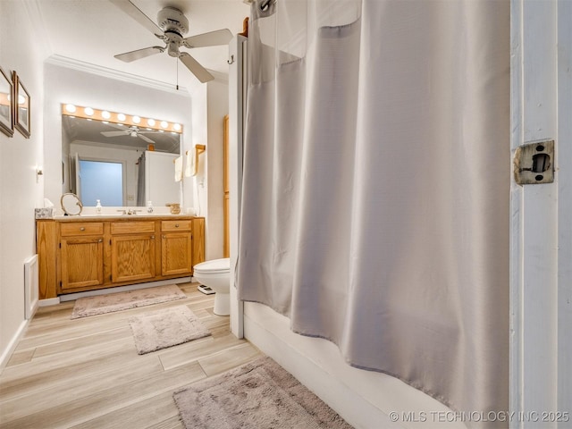 full bathroom featuring ceiling fan, shower / bathtub combination with curtain, toilet, vanity, and ornamental molding