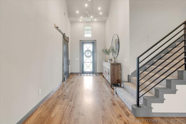4255 S 173rd E Ave, Tulsa, OK 74134 - entryway with a towering ceiling, stairway, a barn door, light wood-style flooring, and a chandelier