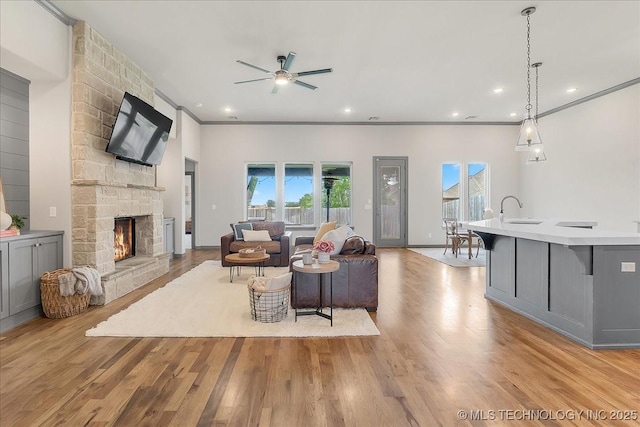 4255 S 173rd E Ave, Tulsa, OK 74134 - living room featuring ceiling fan, a stone fireplace, light wood finished floors, ornamental molding, and recessed lighting