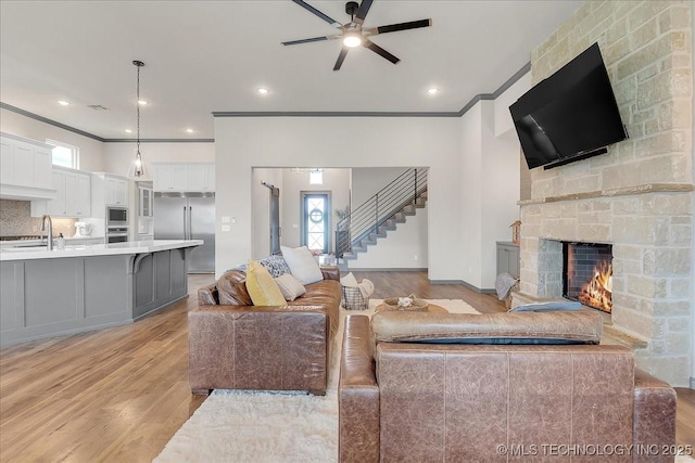 4255 S 173rd E Ave, Tulsa, OK 74134 - living area with light wood-type flooring, ornamental molding, ceiling fan, stairway, and a fireplace