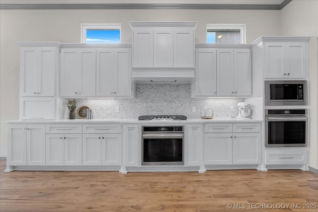 4255 S 173rd E Ave, Tulsa, OK 74134 - kitchen featuring oven, built in microwave, crown molding, white cabinets, and light countertops