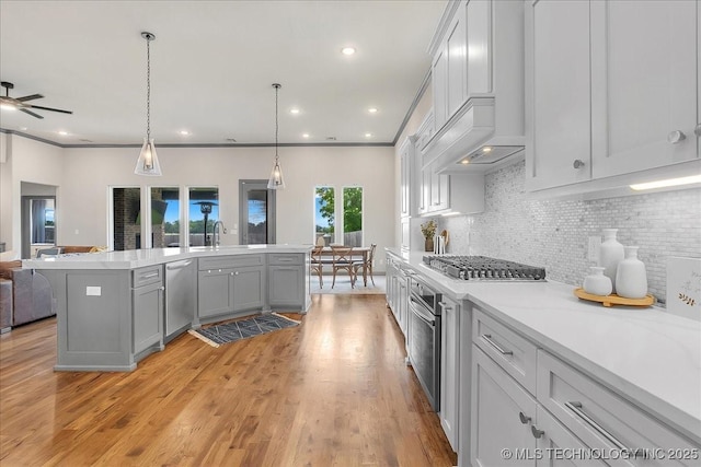 4255 S 173rd E Ave, Tulsa, OK 74134 - kitchen featuring appliances with stainless steel finishes, open floor plan, light countertops, decorative backsplash, and light wood-type flooring