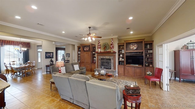 tiled living room featuring a fireplace, crown molding, and ceiling fan with notable chandelier