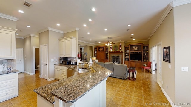 kitchen with backsplash, dark stone counters, stainless steel dishwasher, and ornamental molding