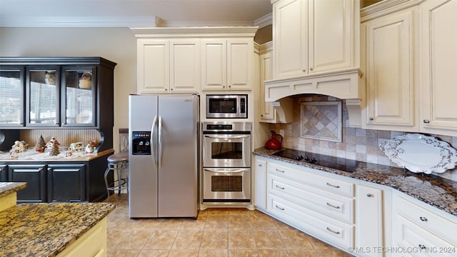 kitchen featuring ornamental molding, stainless steel appliances, light tile patterned floors, and dark stone counters