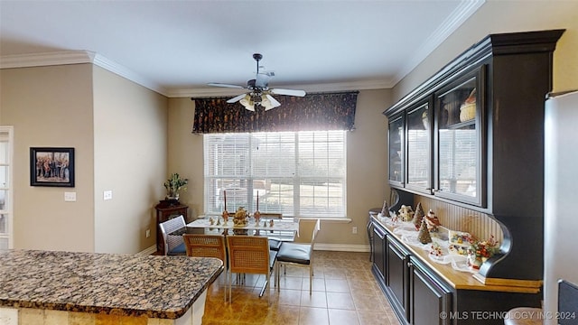 kitchen with tile patterned flooring, ceiling fan, dark stone countertops, and crown molding