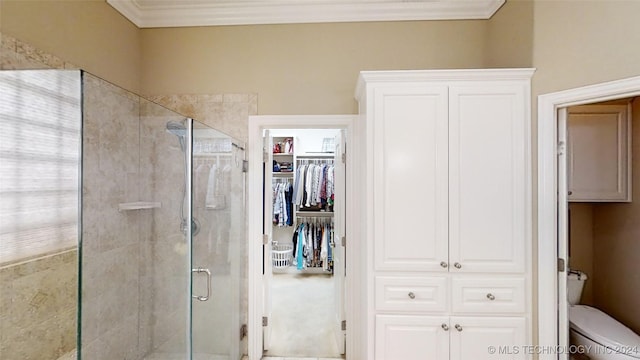 bathroom featuring toilet, a shower with shower door, and ornamental molding