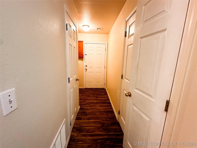 hallway featuring a textured ceiling and dark hardwood / wood-style flooring