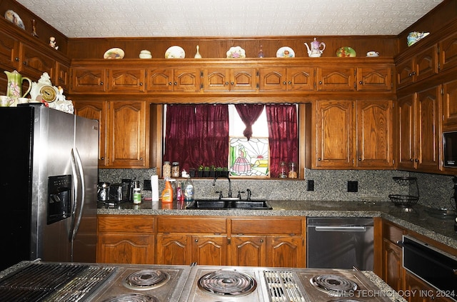 kitchen featuring a textured ceiling, backsplash, stainless steel appliances, and sink