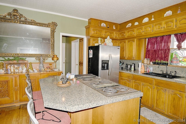 kitchen featuring crown molding, sink, light hardwood / wood-style flooring, appliances with stainless steel finishes, and a kitchen island