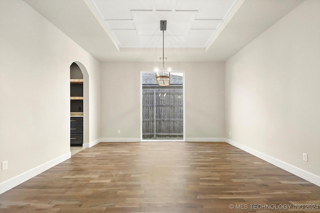 spare room with a raised ceiling and dark wood-type flooring