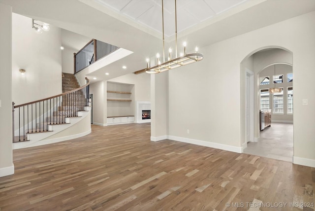 unfurnished living room with a towering ceiling and hardwood / wood-style floors