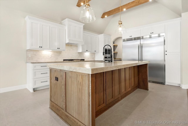 kitchen featuring built in fridge, sink, white cabinetry, and an island with sink