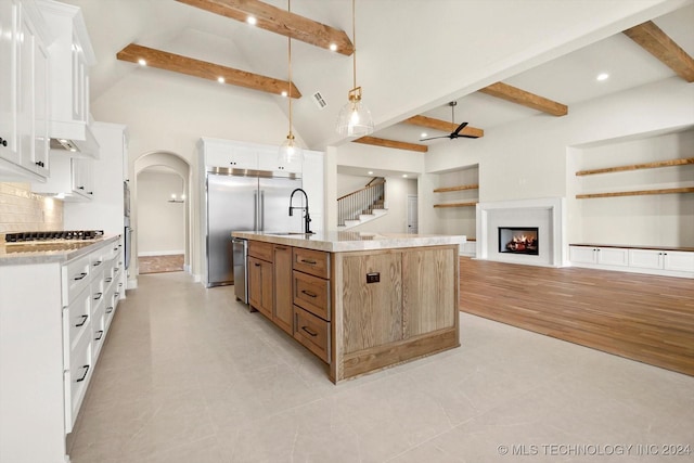 kitchen featuring stainless steel dishwasher, white cabinets, a large island, and decorative light fixtures