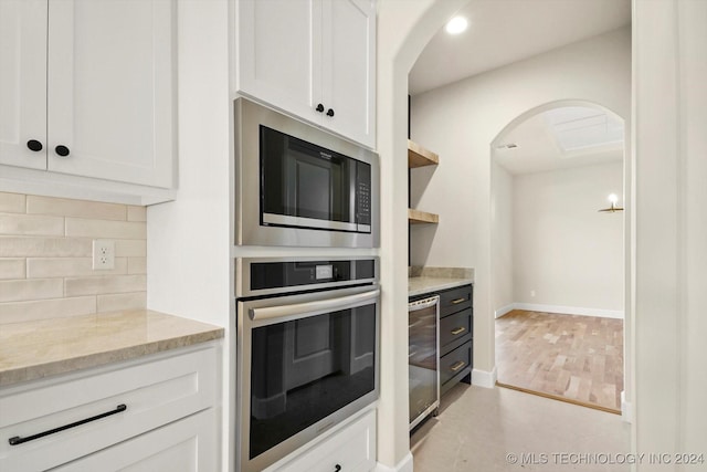 kitchen featuring white cabinets, wine cooler, backsplash, stainless steel oven, and built in microwave