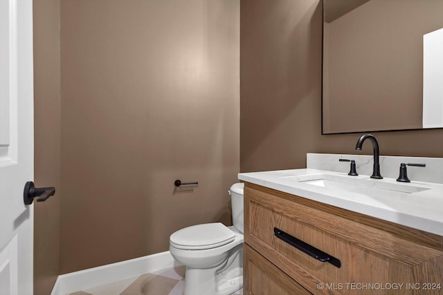 bathroom with toilet, vanity, and tile patterned flooring