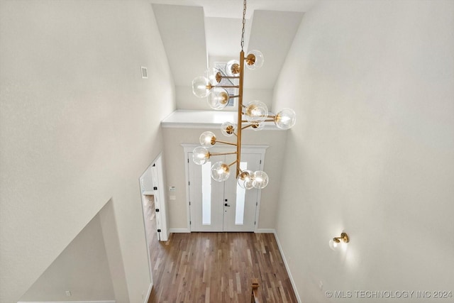 entryway with vaulted ceiling, hardwood / wood-style floors, and a notable chandelier