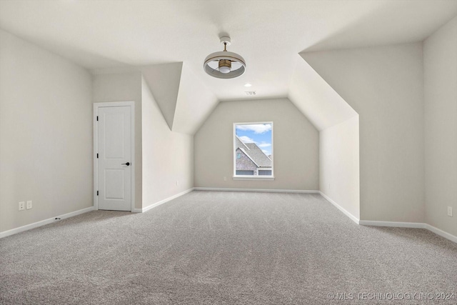 bonus room with lofted ceiling and light colored carpet