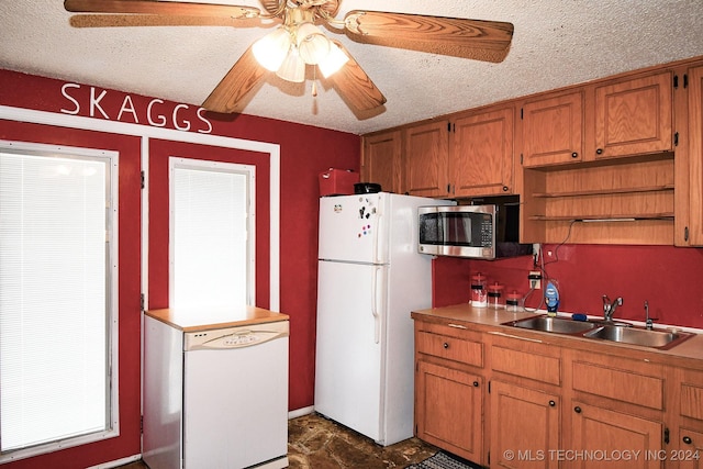 kitchen featuring a textured ceiling, ceiling fan, sink, and white appliances