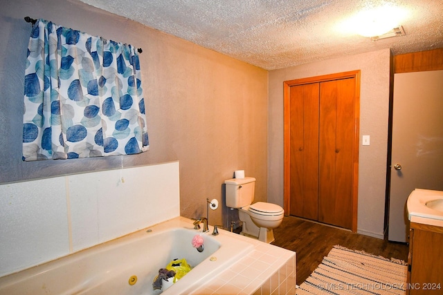 bathroom with a tub to relax in, toilet, wood-type flooring, and a textured ceiling