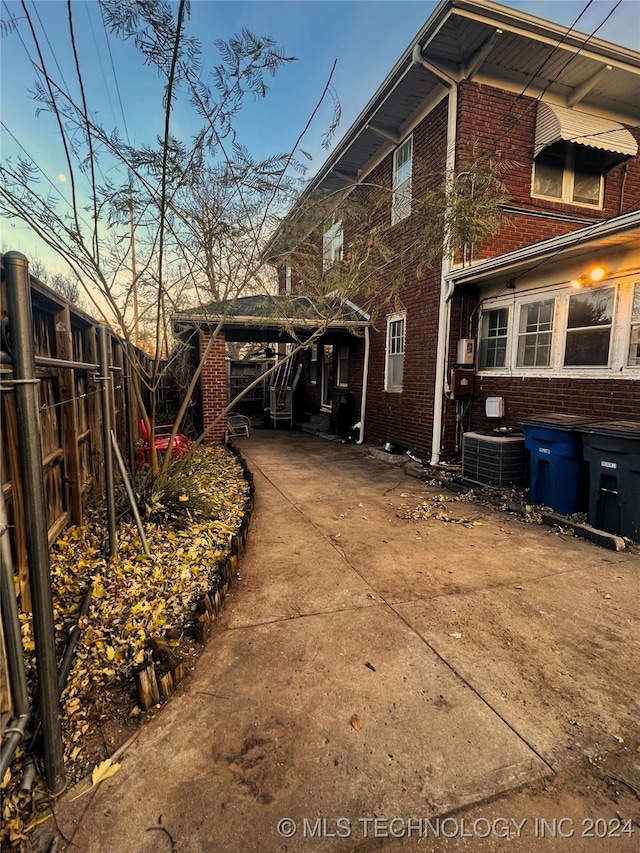 view of side of property with brick siding, fence, and central AC unit