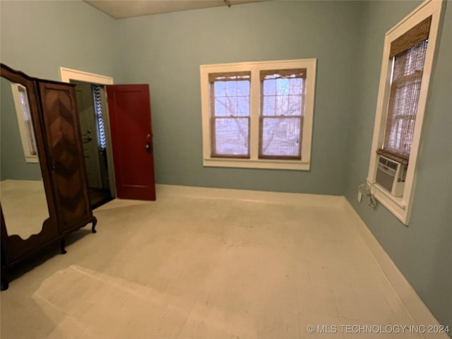 unfurnished bedroom with carpet floors, multiple windows, baseboards, and cooling unit