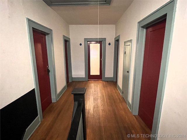 hall featuring wood finished floors, attic access, and baseboards