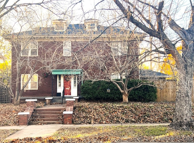 american foursquare style home featuring fence and brick siding