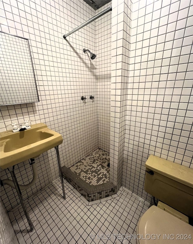 bathroom with tile walls, tile patterned flooring, a shower stall, and toilet