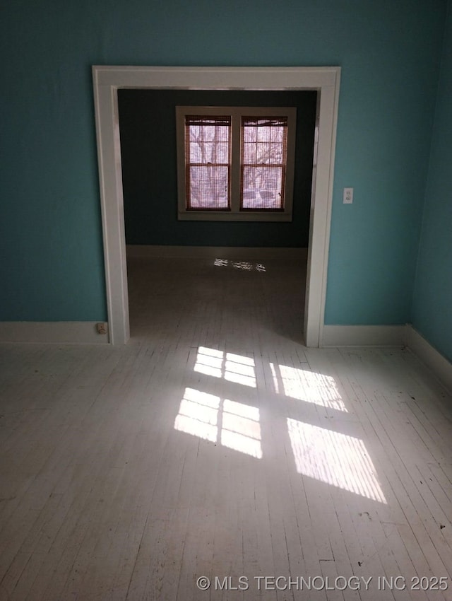 unfurnished room with baseboards and hardwood / wood-style floors