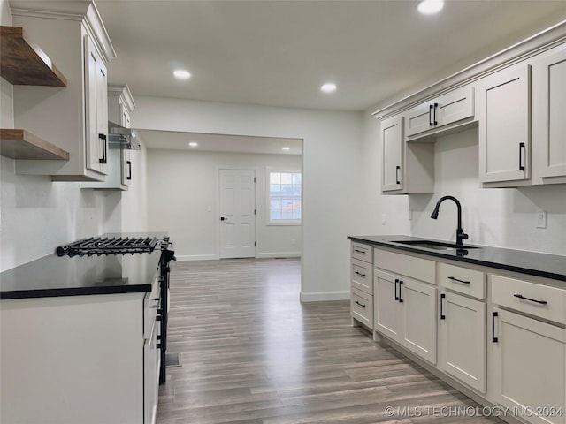 kitchen featuring sink, wall chimney range hood, dark wood-type flooring, and stove