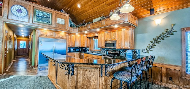 kitchen with wooden ceiling, kitchen peninsula, appliances with stainless steel finishes, and a breakfast bar area