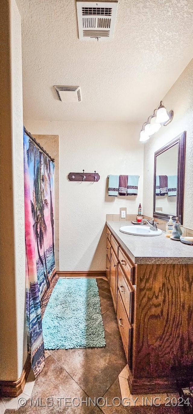 bathroom with tile patterned floors, vanity, and a textured ceiling