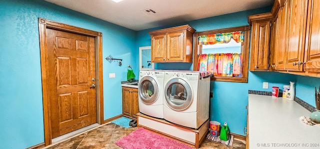 clothes washing area featuring cabinets and washing machine and clothes dryer