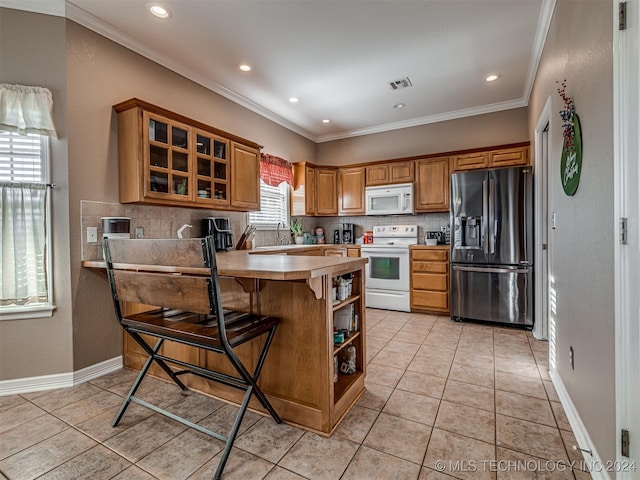 kitchen with a kitchen bar, kitchen peninsula, a healthy amount of sunlight, and white appliances