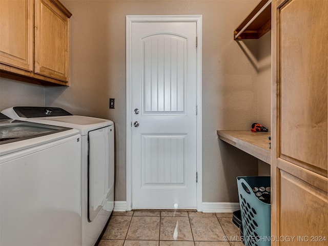 clothes washing area with washing machine and dryer, light tile patterned floors, and cabinets